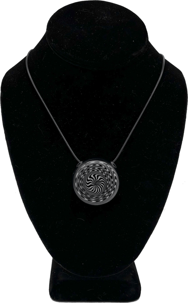 This is the hypnotizing Black & White Swirl Disc Pendant by Biting Glass available at Ritual Colorado. Featuring an intricate black & white pattern accented by deep blue glass on the back this is a bold and stylish jewelry piece.
