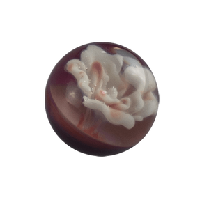 This is an Implosion Flower Marble by Biting Glass available at Ritual Colorado. A handmade borosilicate glass marble featuring vibrant striking purple rainbow glass. 
