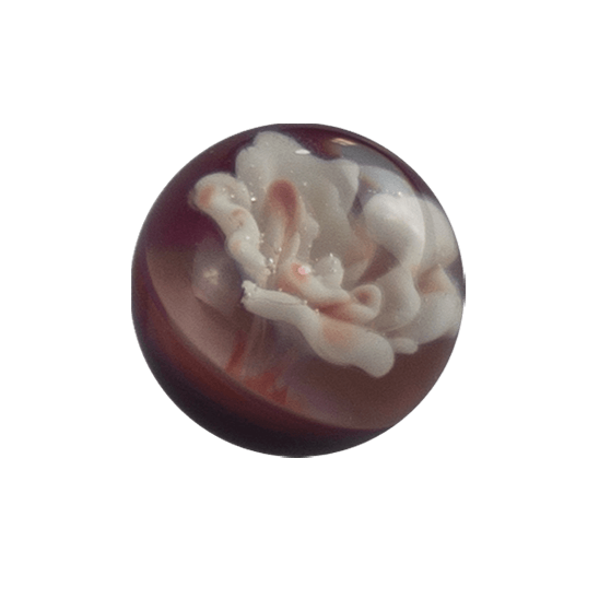 This is an Implosion Flower Marble by Biting Glass available at Ritual Colorado. A handmade borosilicate glass marble featuring vibrant striking purple rainbow glass. 