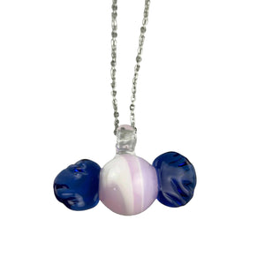 This is the Glass Candy Necklace by Biting Glass available at Ritual Colorado. Featuring a pink & white swirling candy with twisting blue wrappers on each side. This fun necklace comes on an 18" stainless steel chain.