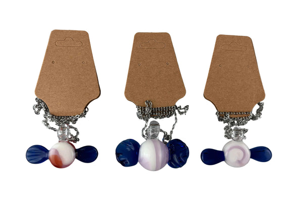 These are Glass Candy Necklaces by Biting Glass available at Ritual Colorado. Featuring pink & white swirling candy with twisting blue wrappers on each side. This fun necklace comes on an 18" stainless steel chain.