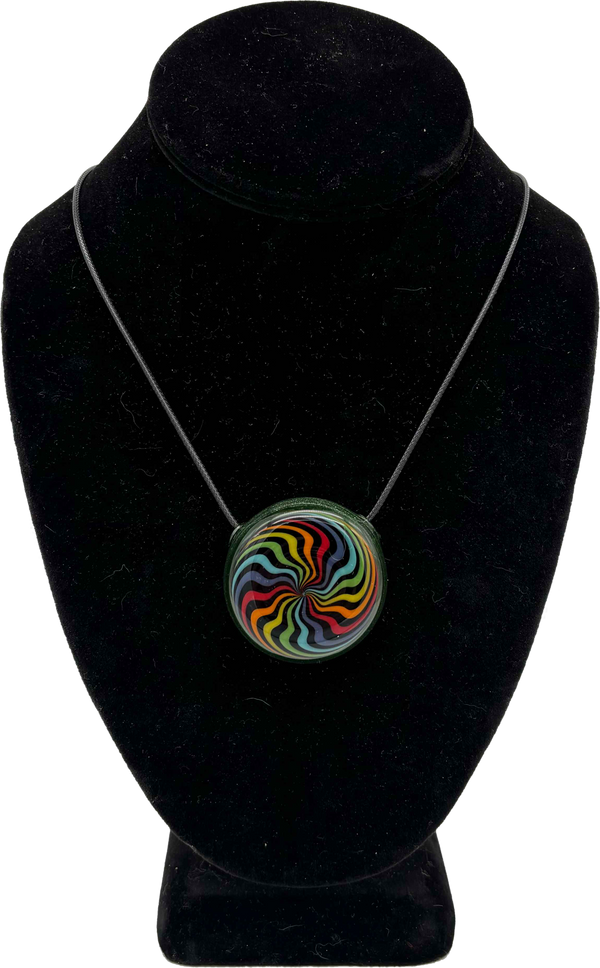 This is the vibrant Rainbow Swirl Disc Pendant by Biting Glass available at Ritual Colorado. Featuring an intricate color pattern accented by sparkle green glass on the back this is a bold and stylish jewelry piece.